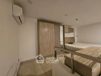 Modern bedroom with sleek design, featuring built-in wardrobe and air conditioning unit.