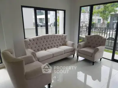 Elegant living room with plush beige sofas and large windows offering natural light and garden views.