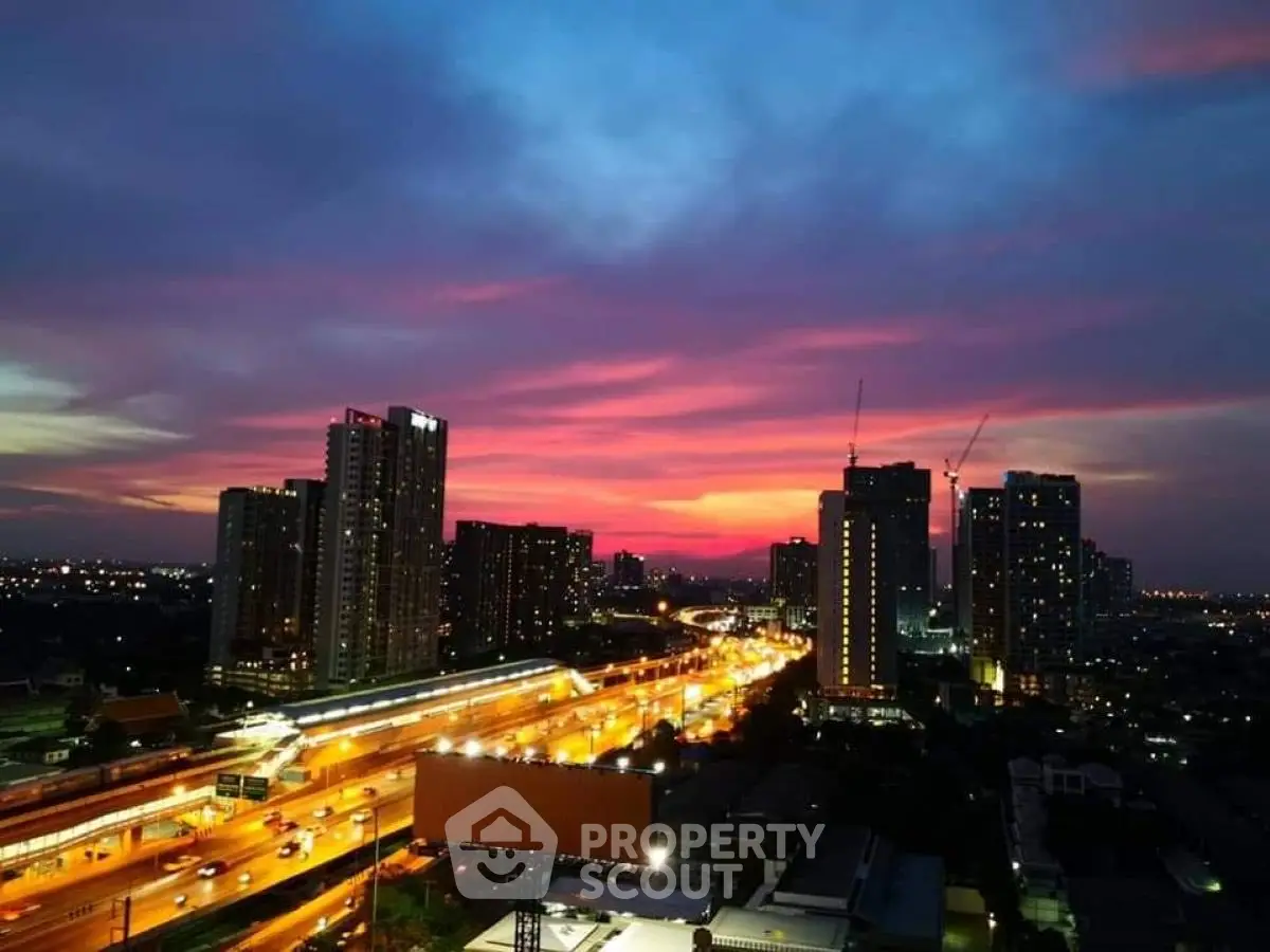Stunning cityscape view with vibrant sunset over urban skyline and highway lights.