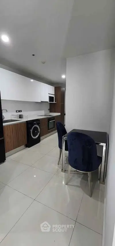 Modern kitchen with sleek appliances and dining area in contemporary apartment.