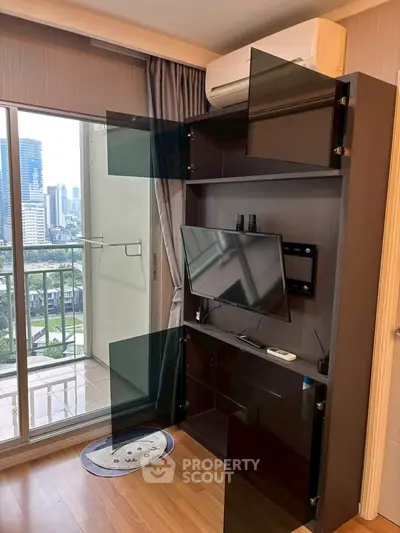 Modern living room with balcony view and sleek entertainment unit in urban apartment.
