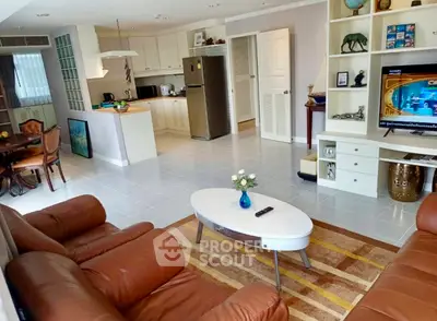 Spacious living room with leather sofas and modern kitchen in open layout apartment.