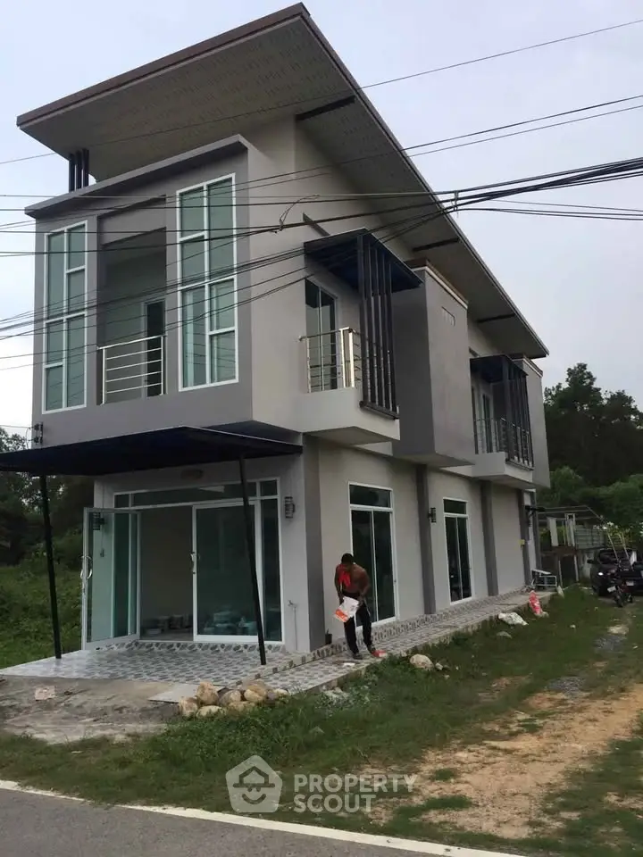 Modern two-story house with large windows and sleek design in a suburban setting.