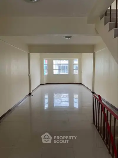 Spacious empty living room with large windows and tiled flooring, ideal for customization.