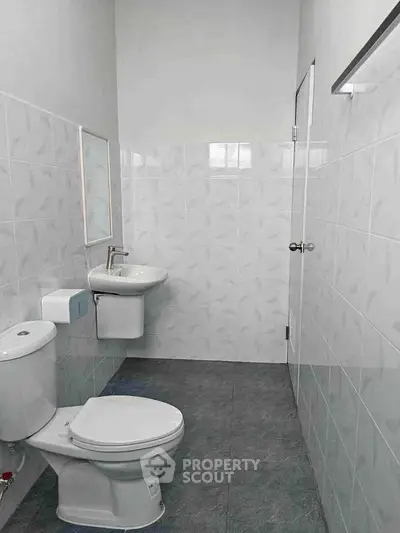 Modern minimalist bathroom with sleek fixtures and tiled walls.