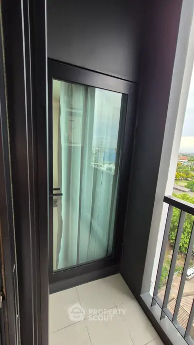 Modern balcony with glass door and city view, perfect for relaxation and enjoying the skyline.