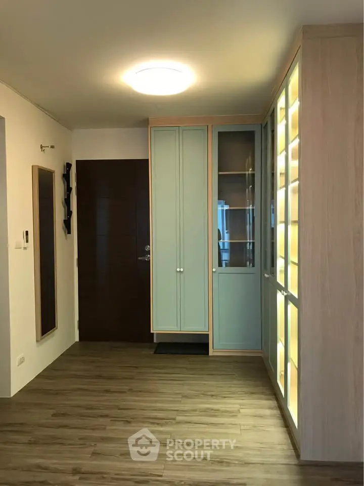 Modern apartment entrance with stylish wooden flooring and built-in storage cabinets.