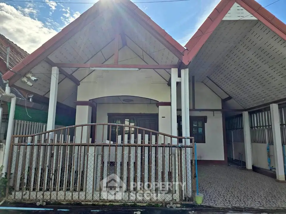 Charming single-story house with unique roof design and gated entrance, perfect for family living.