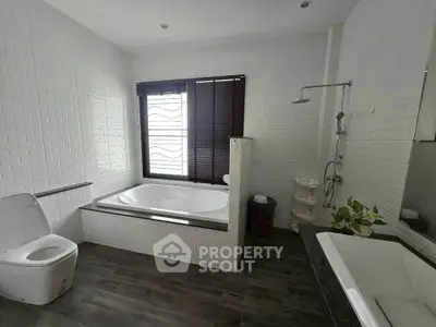 Spacious modern bathroom with bathtub and shower in elegant white decor.