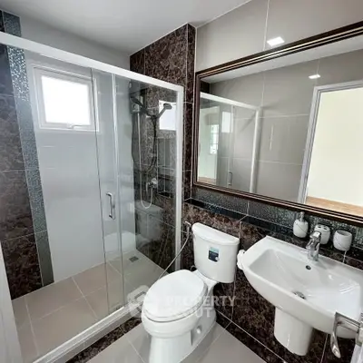 Modern bathroom with glass shower, sleek fixtures, and elegant tile design.
