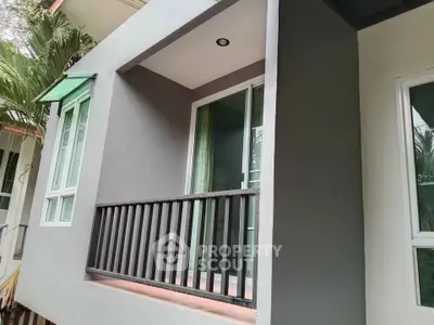 Modern apartment exterior with small balcony and sliding glass doors.