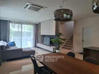 Modern living room with stylish furniture and open layout, featuring a cozy dining area and staircase.