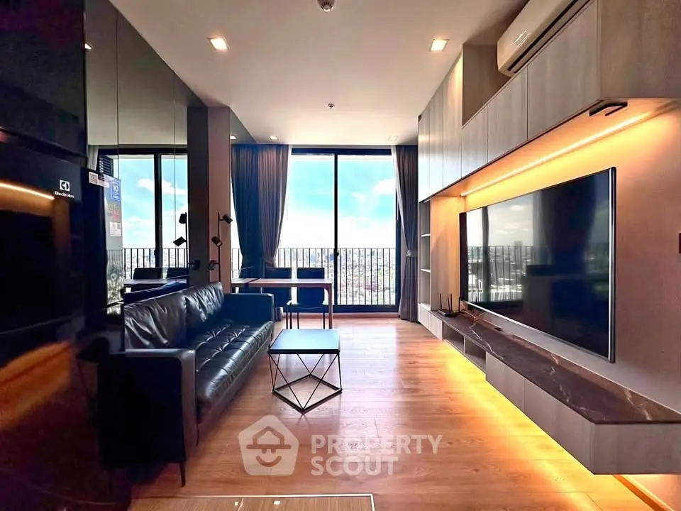 Modern living room with large TV, sleek furniture, and floor-to-ceiling windows offering stunning city views.