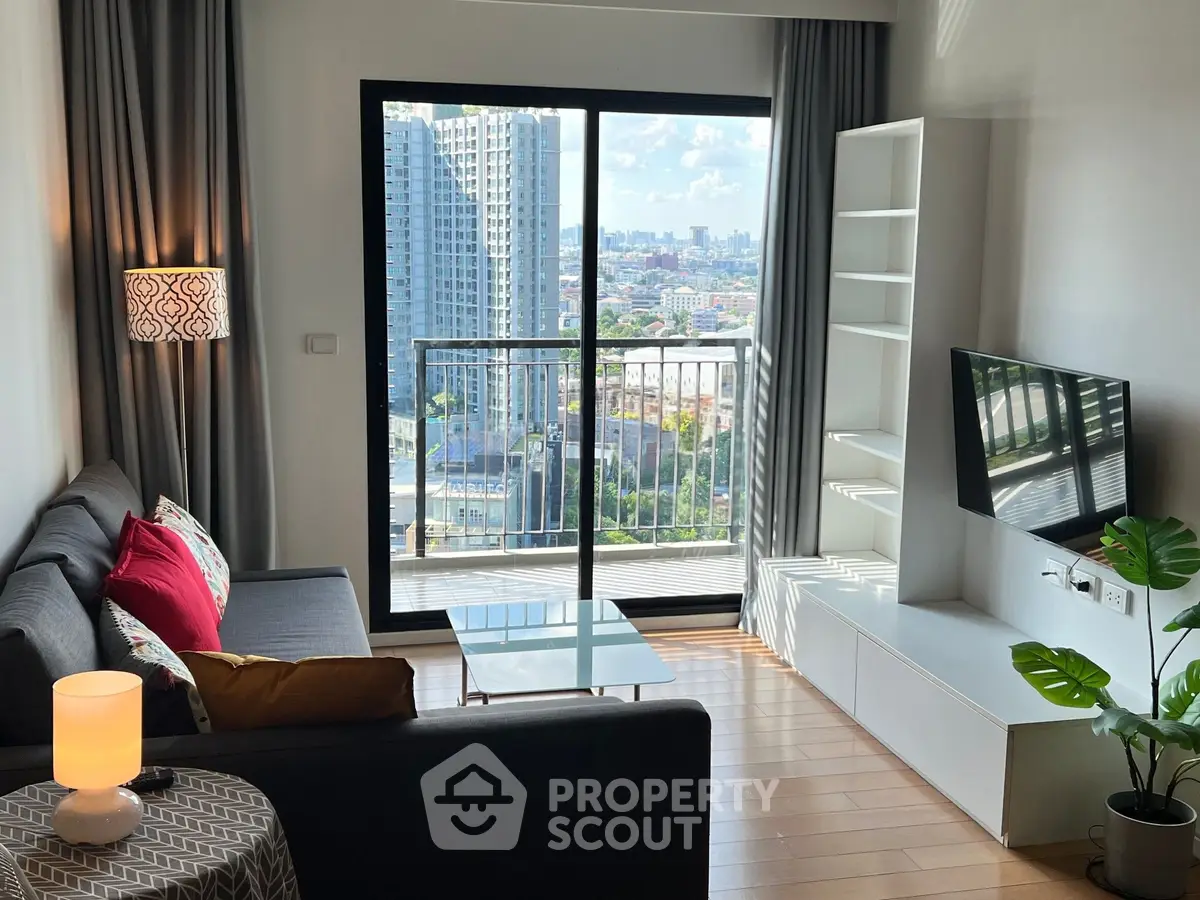 Modern living room with city view, stylish decor, and balcony access in a high-rise apartment.
