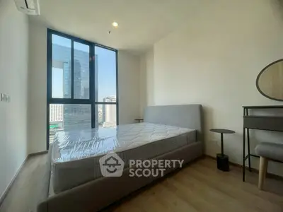 Modern bedroom with large window and city view, featuring a stylish bed and elegant decor.