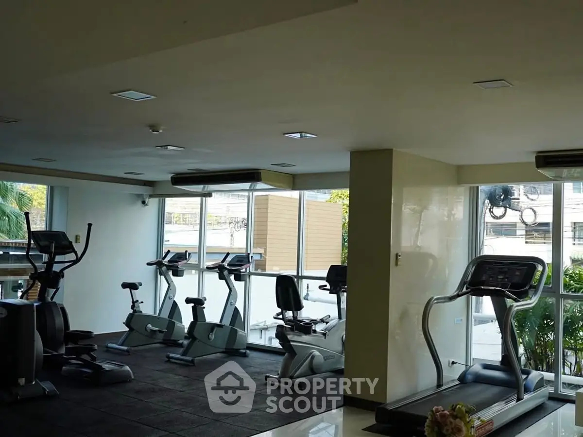 Modern gym with exercise equipment and large windows offering natural light.