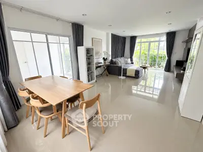 Spacious modern living room with dining area and large windows offering garden views.