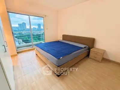 Spacious bedroom with city view and balcony access in modern apartment.