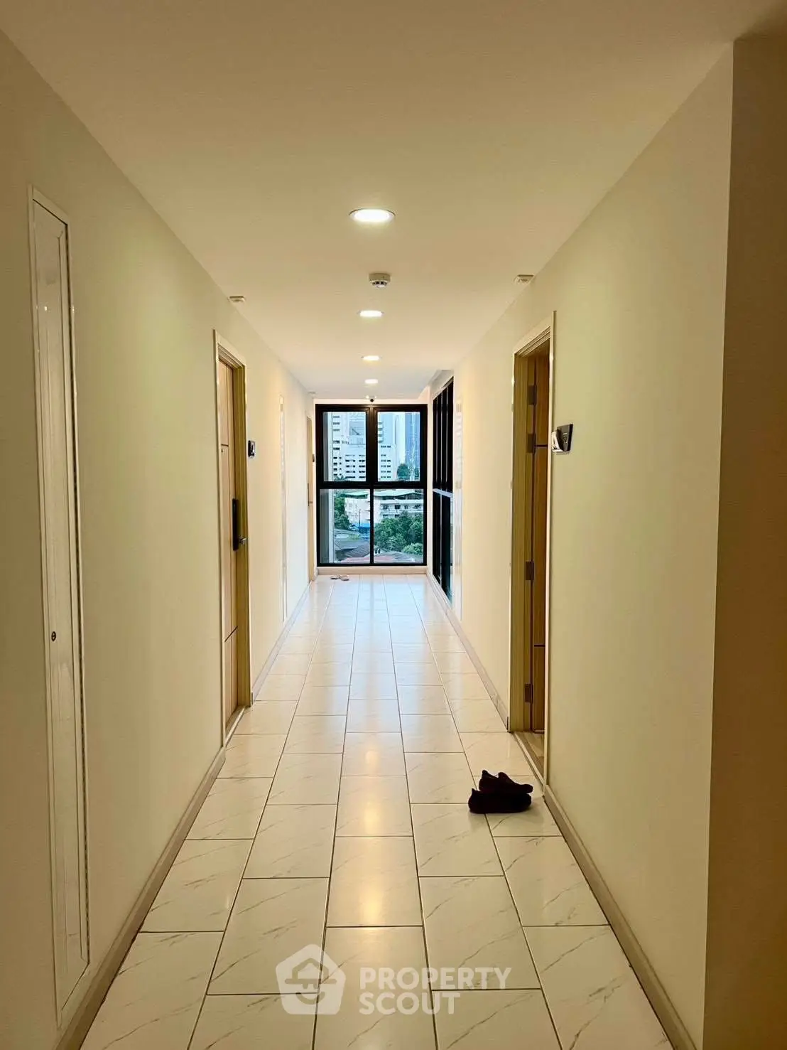 Bright corridor with tiled flooring leading to a balcony with city view