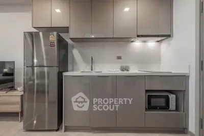 Modern kitchen with sleek cabinetry, stainless steel fridge, and built-in microwave in a stylish apartment.