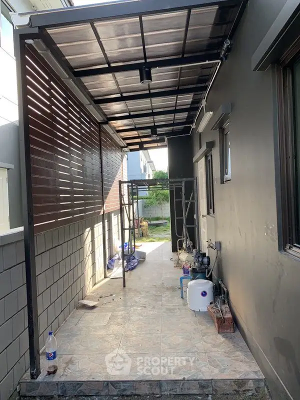 Modern covered outdoor walkway with tiled flooring and utility area.