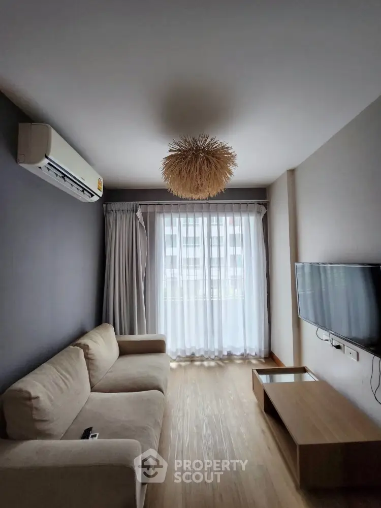 Modern living room with natural light, cozy sofa, and wall-mounted TV