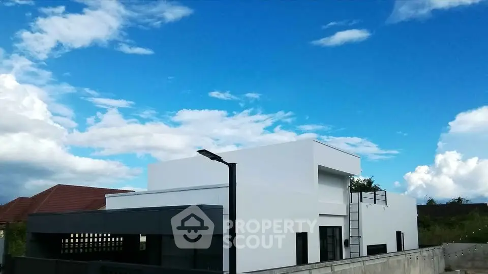 Modern minimalist white building with clear blue sky backdrop, showcasing sleek architectural design.