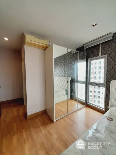 Modern bedroom with mirrored wardrobe and elegant wallpaper in high-rise apartment