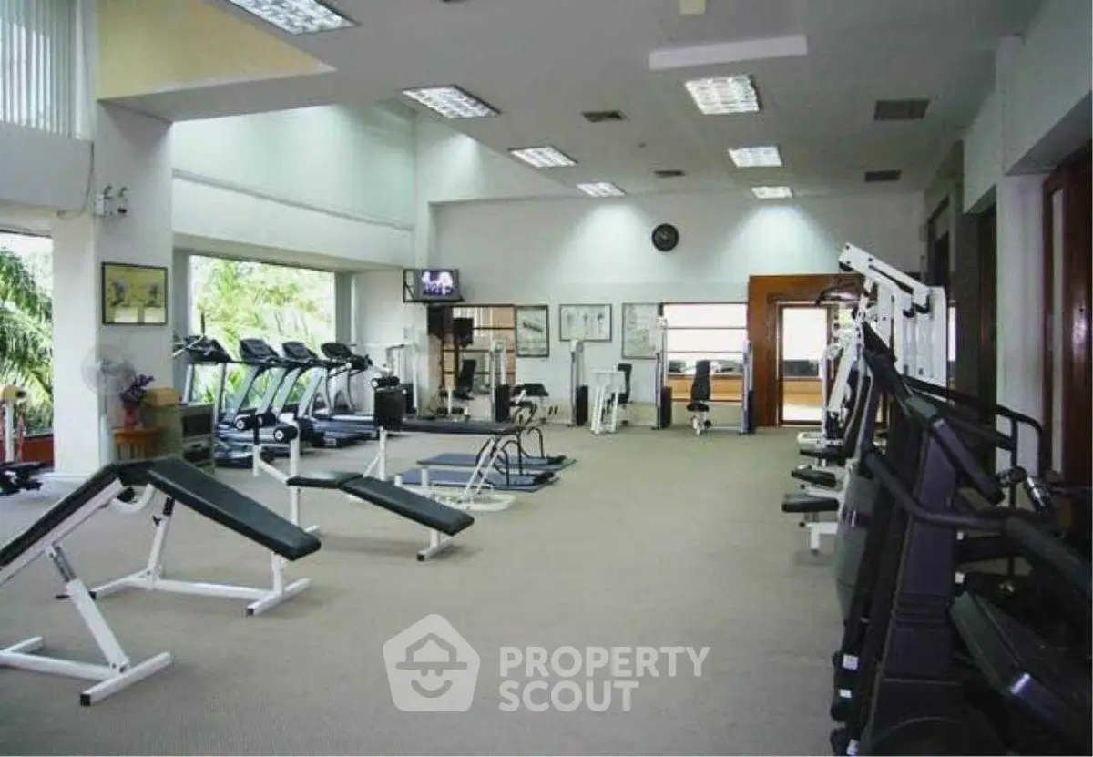 Spacious gym with modern equipment and large windows for natural light.