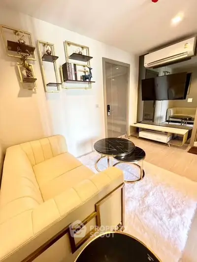 Modern living room with elegant decor, featuring a plush sofa, stylish coffee tables, and wall-mounted TV.