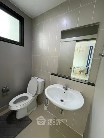 Modern bathroom with sleek design and neutral tones, featuring a toilet and sink.