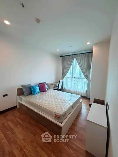 Spacious bedroom with large window and wooden flooring in modern apartment