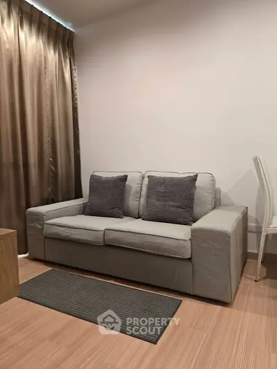 Cozy living room with modern gray sofa and elegant curtains, perfect for relaxation.
