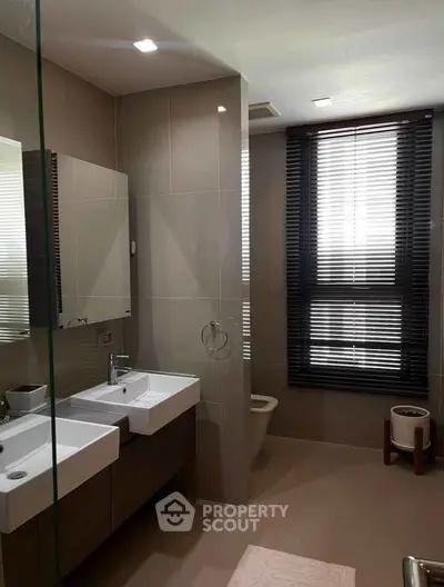 Modern bathroom with dual sinks and large window with blinds