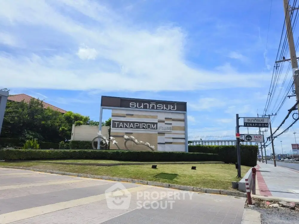 Tanapirom residential entrance with clear blue sky and lush greenery