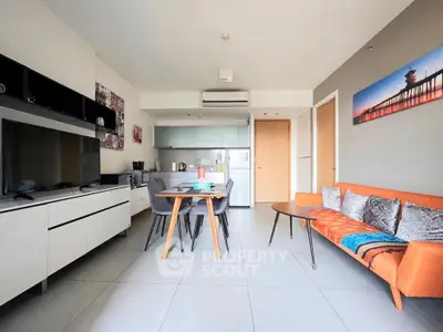 Modern open-plan living room with sleek kitchen and vibrant orange sofa