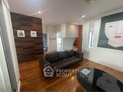 Modern living room with stylish decor and wooden flooring, featuring a leather sofa and contemporary artwork.
