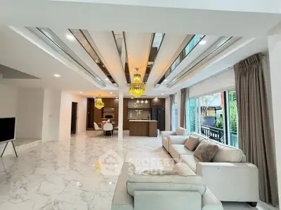 Luxurious open-plan living room with elegant chandeliers and modern kitchen in a spacious home.