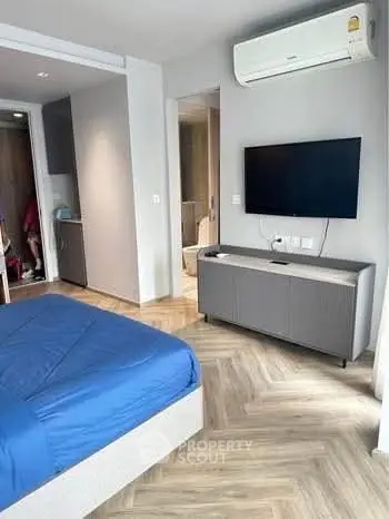 Modern bedroom with sleek design, featuring a wall-mounted TV and stylish flooring.