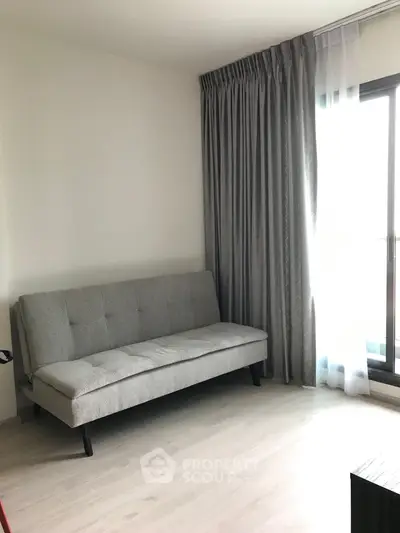 Modern living room with sleek gray sofa and floor-to-ceiling window curtains.
