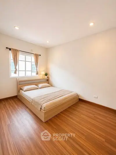 Spacious bedroom with wooden flooring and natural light