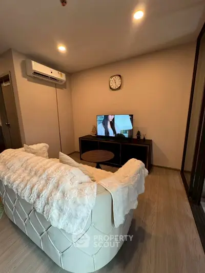 Cozy living room with plush sofa and wall-mounted TV, perfect for relaxation.