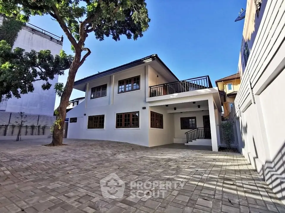 Spacious modern house with large driveway and lush tree in serene neighborhood.