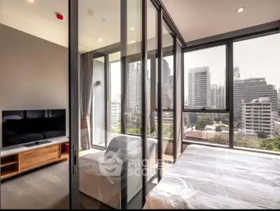 Modern bedroom with city view and glass partition, featuring sleek TV setup and cozy seating area.