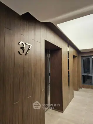 Modern elevator lobby with sleek wood paneling and floor number 37 displayed.