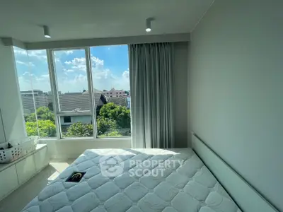 Bright bedroom with large windows and scenic view, featuring a comfortable bed and modern decor.