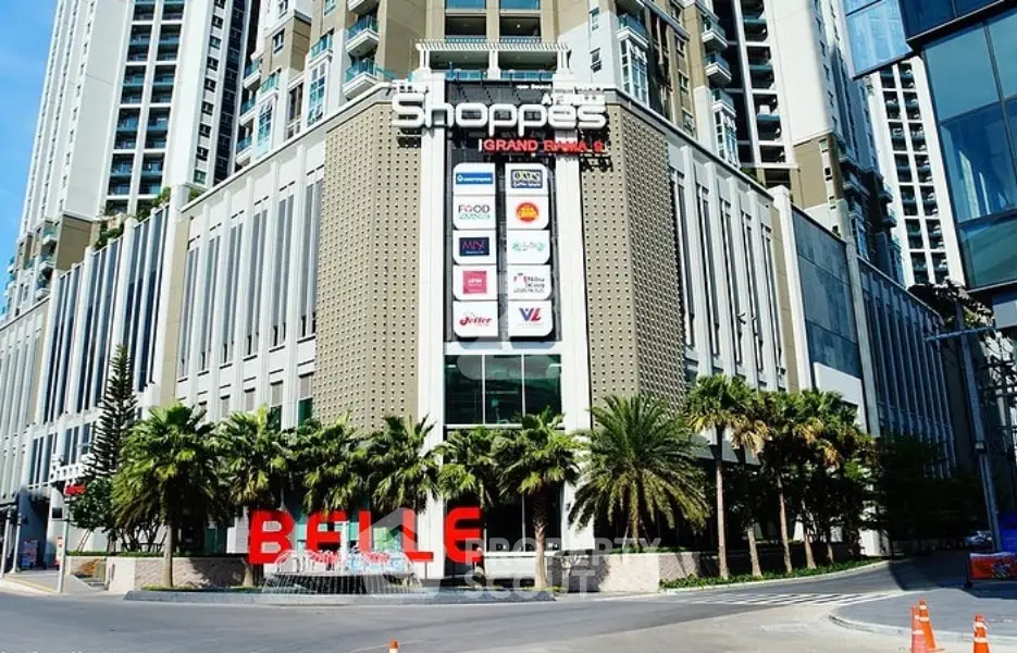 Modern commercial building with palm trees and prominent signage in urban setting.