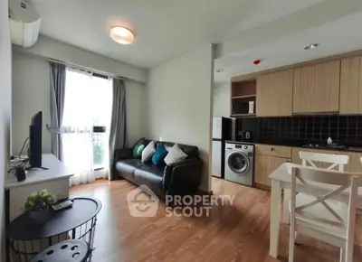 Modern living room with open kitchen, featuring sleek furniture and natural light.