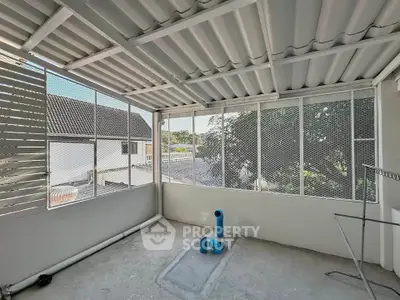 Spacious balcony with metal roofing and mesh walls offering outdoor views