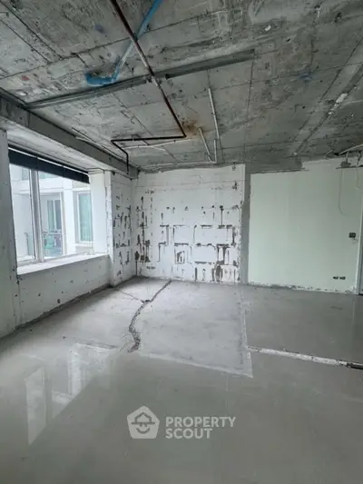 Spacious unfinished room with large window and concrete walls, ideal for customization.